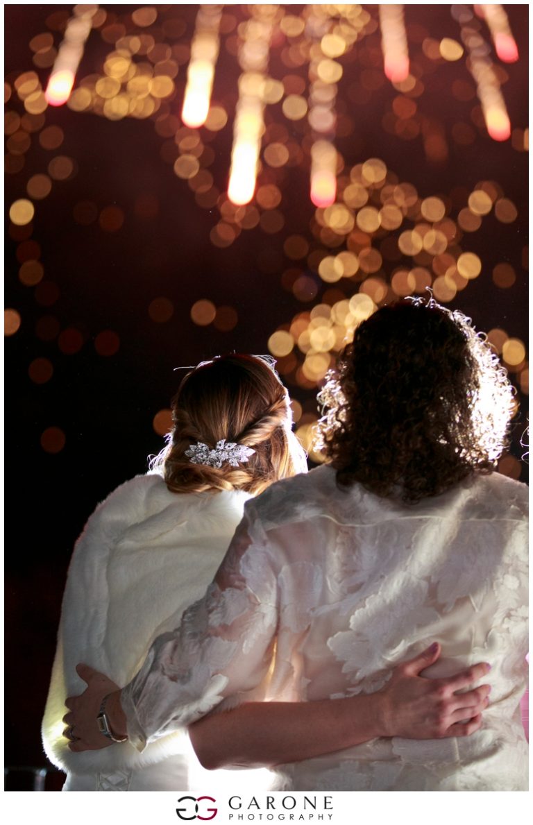 Two people watching bright fireworks at night.