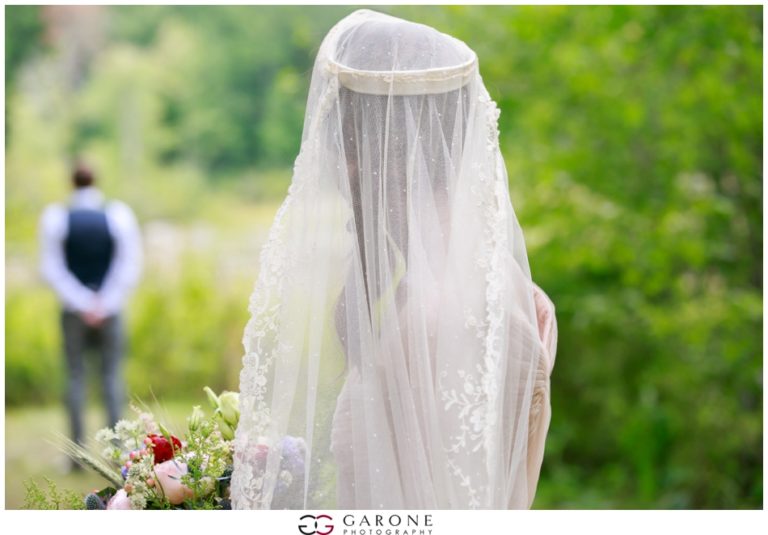 Bride in a delicate white veil and gown outdoors.