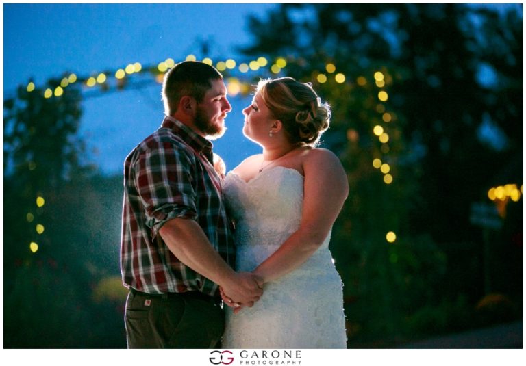 Couple sharing a romantic moment outdoors at twilight with twinkling lights.
