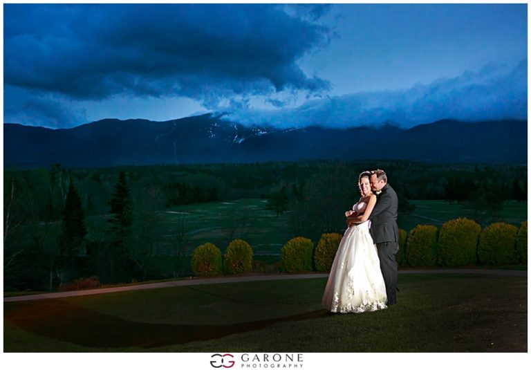 Bride and groom share a dance under a dramatic evening sky.