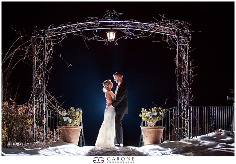 Couple sharing a romantic moment under a lighted arch at night.